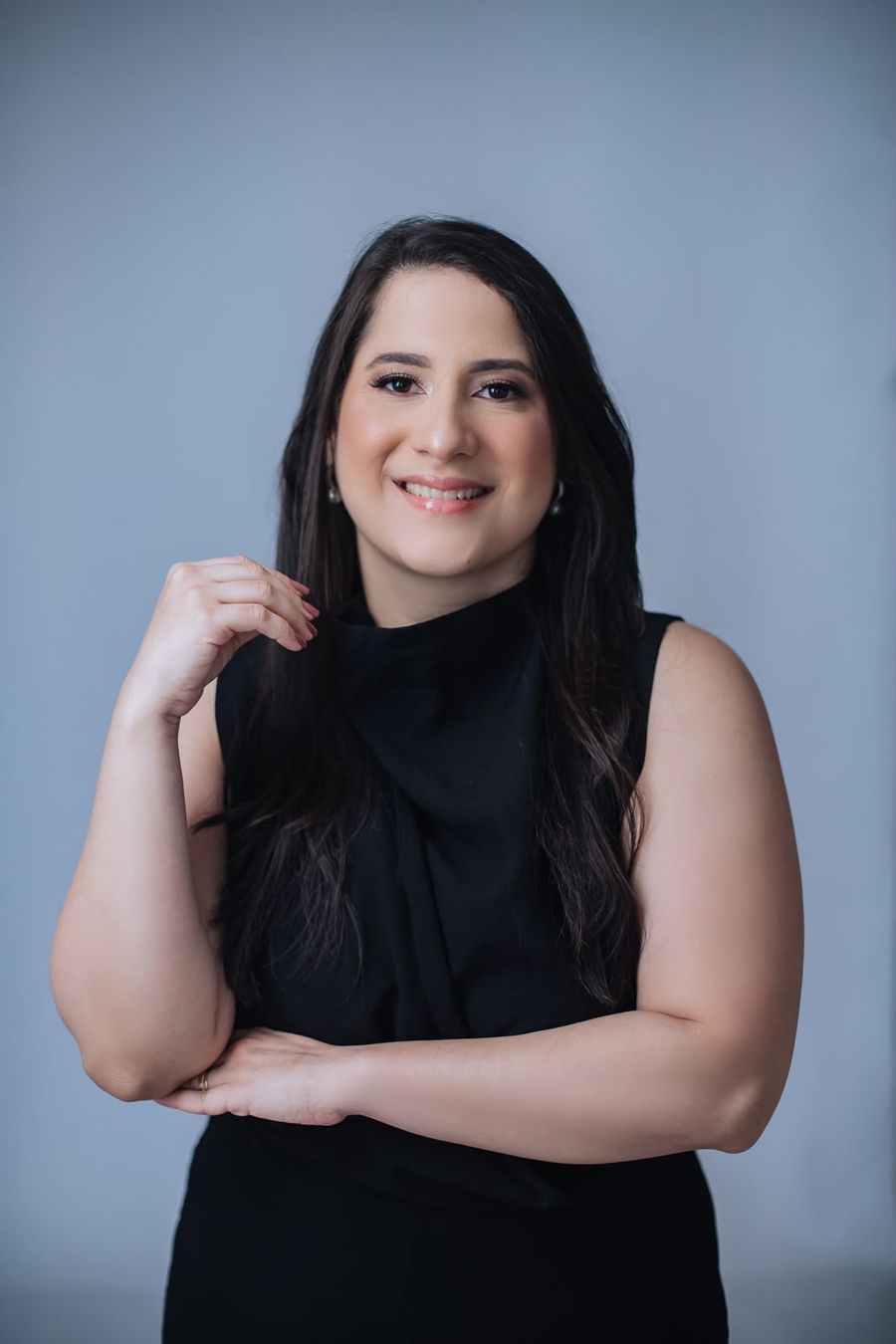 Dra. Renata Ramos sorrindo, com a mão no colarinho da blusa preta